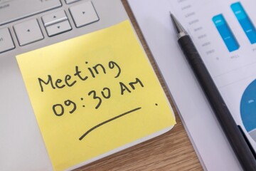 Yellow sticky note with the word Meeting 09:30 AM on a laptop. Meeting schedule concept.