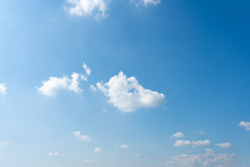 Fluffy white clouds drift across a clear blue sky, painting a breathtaking summer day