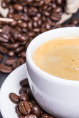 White cup of coffee and roasted fragrant dark coffee grains