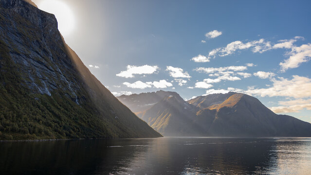Sonnenstrahlen fallen &uuml;ber den Berg im Hjoerundfjord bei Urke