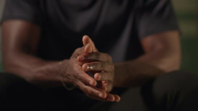 Stress and anxiety, young African man having shaking hands and hand tremors in his bedroom at night.