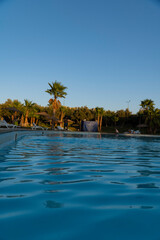 Stunning landscape, swimming pool blue sky with clouds. Oriental resort hotel in Marrakech. Fantastic relax and peaceful vibes, chairs, loungers under umbrella and palm leaves. Luxury travel vacation