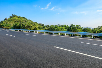 Asphalt highway road and green forest nature landscape under blue sky. Car background.