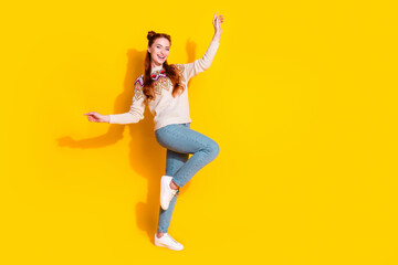 Photo portrait of attractive young woman raise hands dancing dressed stylish knitted warm outfit isolated on yellow color background