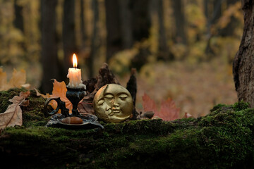 moon amulet and burning candle in forest, dark nature background. Samhain, Halloween. Witchcraft,...