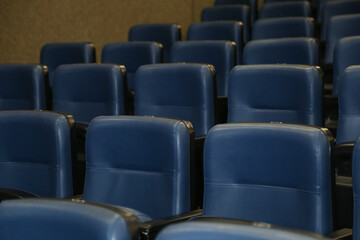 Fileiras de assentos vazios, de cor grafite, no teatro.