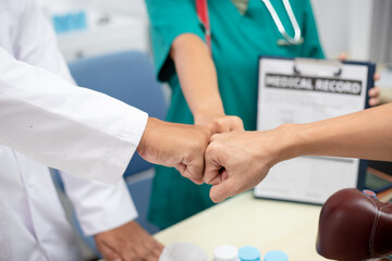 A multi-ethnic medical team is meeting with doctors in white lab coats and surgical gowns sitting at tables to discuss patient records.