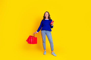 Full length photo of lovely pensioner lady device shopping bags dressed stylish blue knitted garment isolated on yellow color background