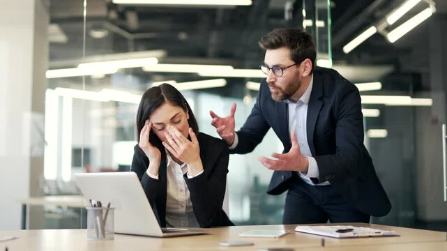 Angry boss quarreling with young upset female subordinate while sitting at workplace in business office. Furious employer arguing talking about problems. Dissatisfied manager unhappy with work results