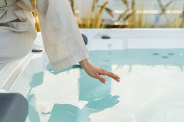 Woman touching the water in hot tub to check temperature before taking a bath