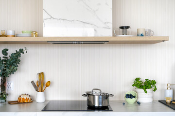Modern kitchen countertop with stove, stainless steel pot and accessories on table
