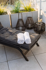 White rolled towels on lounger on a patio