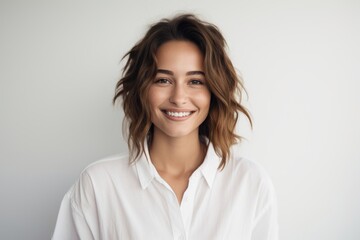 Portrait of a smiling woman in her 20s wearing a simple cotton shirt isolated on white background