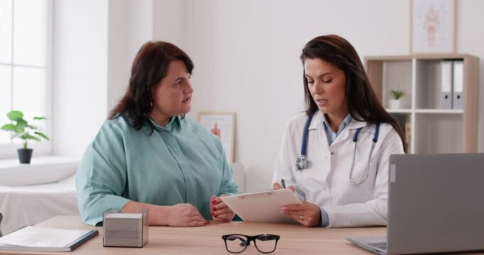 Doctor gives consultation to fat large chubby overweight obese woman, answers questions, explains, prescribes diet, shares advice on wellness, lifestyle, nutrition, weight loss and body mass control