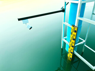 water level gauge at a reservoir, featuring a yellow measurement scale and a camera sensor to...