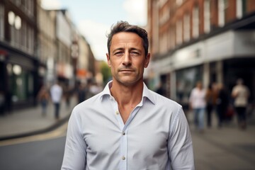 Fototapeta premium Portrait of a glad man in his 40s wearing a simple cotton shirt over busy urban street