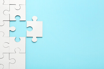 White puzzle pieces on light blue background, top view. Space for text