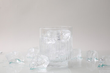Refreshing water in glass with ice cubes on light background
