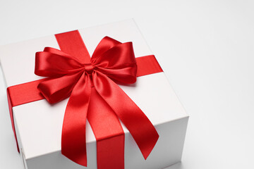 Gift box with red bow on light grey background, closeup