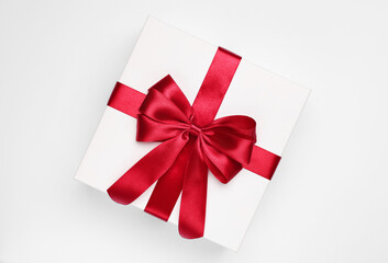 Gift box with red bow on light grey background, top view