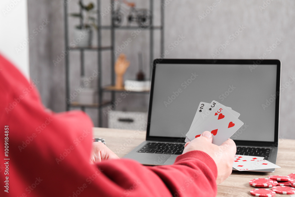 Sticker Online poker. Man with playing cards, chips and laptop at wooden table indoors, closeup