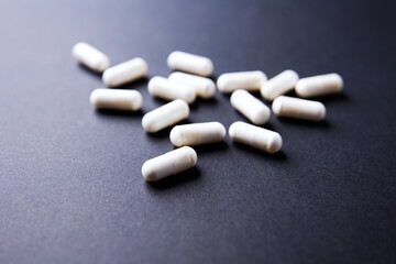 Creatine capsules on dark paper background. Soft focus. Copy space.	