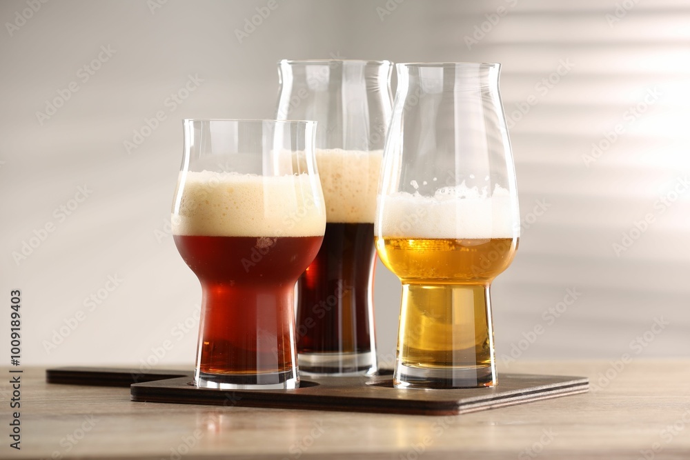 Sticker Glasses with different types of beer on wooden table indoors