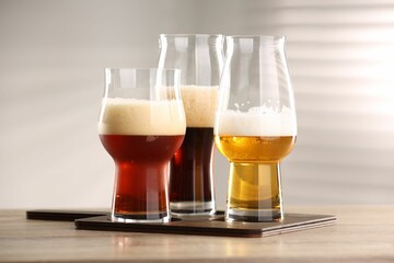 Glasses with different types of beer on wooden table indoors