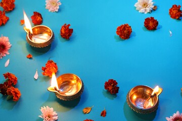 Diwali celebration. Diya lamps and beautiful flowers on blue background, above view