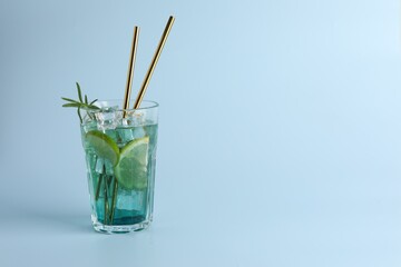 Tasty refreshing drink with straws in glass on light blue background, space for text