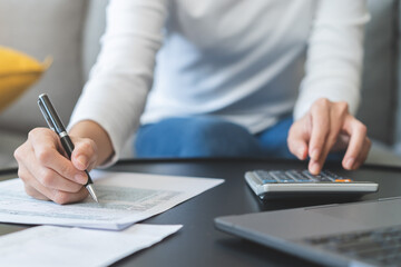 Deduction planning concept. Asian young woman hand using calculator to calculating balance prepare tax reduction income, cost budget expenses for pay money form personal Individual Income Tax Return.