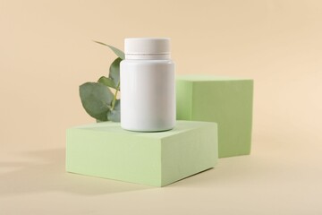 Plastic medical bottle, eucalyptus leaves and podiums on beige background