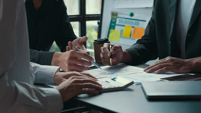 Business team members are discussing financial data and using a calculator to calculate the numbers