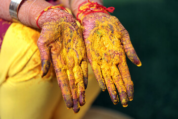 bride and groom's hands adorned with intricate henna designs and vibrant bangles, during a traditional Indian wedding ritual.