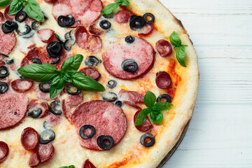 Pizza with mozzarella cheese , salami sausages , olives , and basil