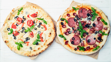 2 pizza with mozzarella cheese , salami sausages , olives , chicken , pineapple and tomatoes