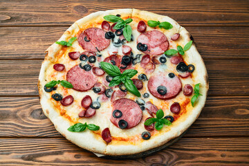 Pizza with mozzarella cheese , salami sausages , olives , and basil