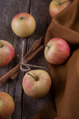 Cinnamon sticks, apples towel on wooden table