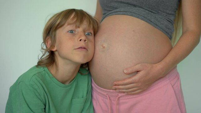 A pregnant woman and her elder son share a magical moment. The boy listens to sounds in her belly and is surprised when he feels the baby kicking. This video beautifully captures the joy and wonder of