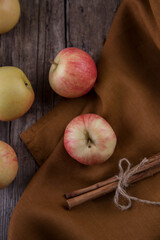 Cinnamon sticks, apples towel on wooden table
