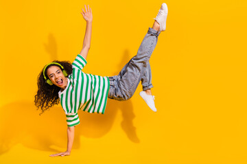 Full body portrait of nice young girl headphones music breakdance wear striped t-shirt isolated on yellow color background