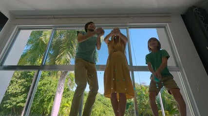 A pregnant woman, her husband, and their elder son conduct a gender reveal party. Throw blue confetti into the air in their excitement after they discovered that they are going to have a boy