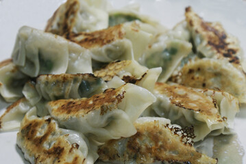Japanese gyoza are pan-fried dumplings filled with minced pork, cabbage, garlic, and ginger, in thin dough. They are crispy outside, juicy inside, and served with a soy sauce and vinegar dip.