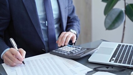 Fototapeta premium Businessman analyzing financial data on laptop and calculator. Close-up of a professional auditor working on financial reports. Business concept
