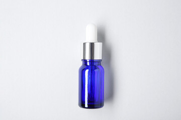 Essential oils in bottle on light background, top view