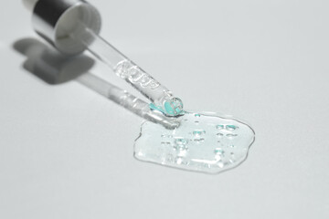 Pipette with cosmetic serum on light background, closeup