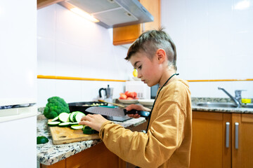 Boy cutting vegetables in the kitchen at home. healthy lifestyle