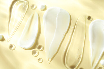 Smears of different cosmetic products on beige background, flat lay