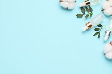 Cosmetic products. Essential oil, leaves and cotton flowers on light blue background, flat lay. Space for text