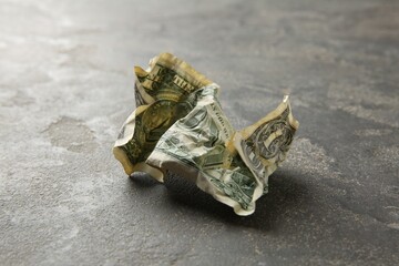 One crumpled dollar banknote on grey table, closeup